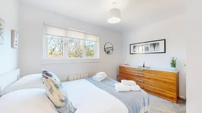a bedroom with a bed and a dresser and a window at Cairn BNB Introduces Mavisbank Gardens - where homely charm meets modern living in Glasgow