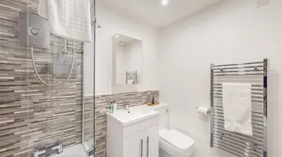 a white bathroom with a sink and a shower at Cairn BNB Introduces Mavisbank Gardens - where homely charm meets modern living in Glasgow