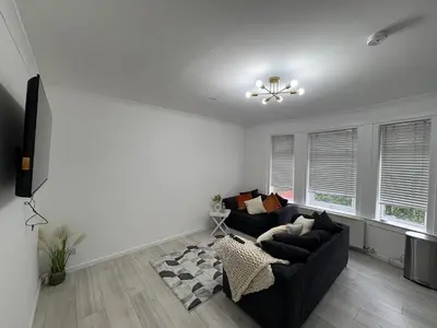 a living room with a black couch and windows at Cozy 3 Bed Home, Free Parking 8 min to City Centre in Cowlairs