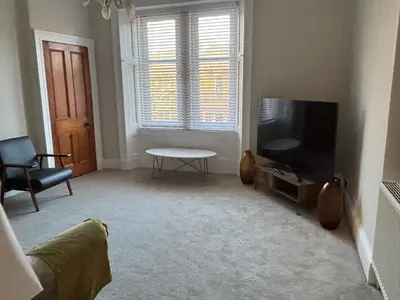 a living room with a flat screen tv and a table at Crescent Corner 44 Seamore Street 3 Bedroom in Largs