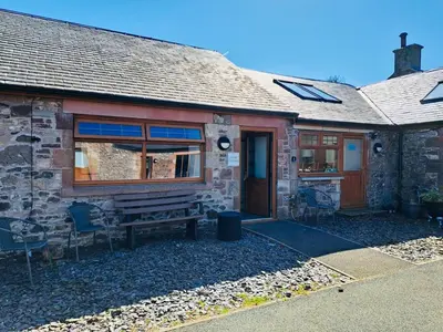 a stone house with a bench in front of it at Clyde Cottage in Lamington