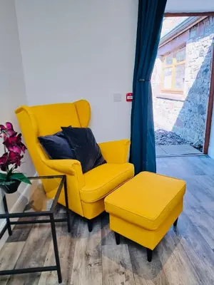 a yellow chair and a stool in a room at Clyde Cottage in Lamington