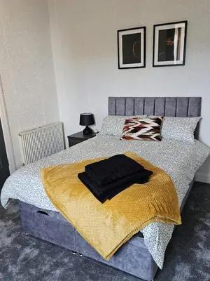 a bedroom with a bed with a yellow blanket at Addex Apartment in Dunfermline