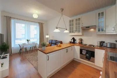 a kitchen with white cabinets and a dining room with a table at Central 1-bed flat - Walk to shops, pubs and station in Saltcoats