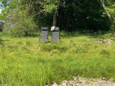 two chairs sitting in the grass in a field at The Hidden Shepherds Hut- Off Grid Retreat in Castle Douglas
