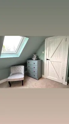 a room with a barn door and a chair and a dresser at The Bothy, Callander in Callander