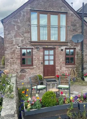 a stone house with two chairs in front of it at Loch Leven Loft in Milnathort