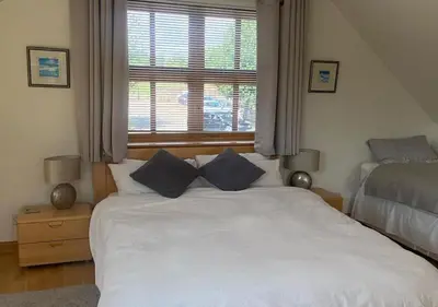a bedroom with a white bed with two blue pillows at Loch Leven Loft in Milnathort