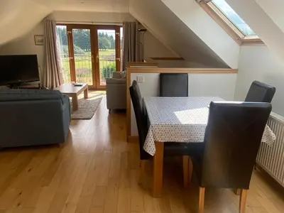 a dining room with a table and chairs and a couch at Loch Leven Loft in Milnathort
