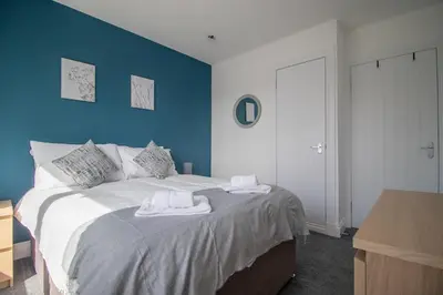 a blue bedroom with a bed with towels on it at Highfield Apartment- 2 Bed in Motherwell close to centre in Motherwell