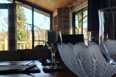 a table with two wine glasses on a table at Wildwood Cabin - Sleeps 6 Hot Tub & Parking in Beattock