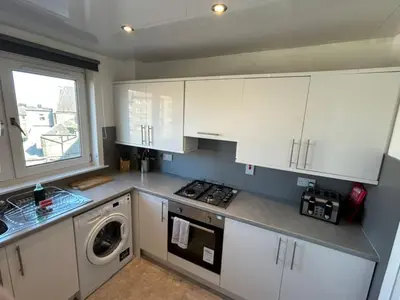 a kitchen with white cabinets and a washing machine at 3-Bed Apartment Central Greenock in Greenock