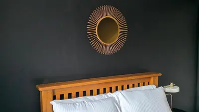 a mirror on a black wall with a bed and a mirror above it at The Ansi8 in Livingston