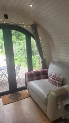 a living room with a couch in front of a window at Squirrels Wood Lodge, nr Glencoe, dog friendly in Acharra