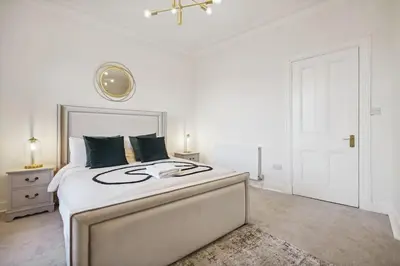 a white bedroom with a large bed and a door at Large Terraced Home with Parking in Glasgow