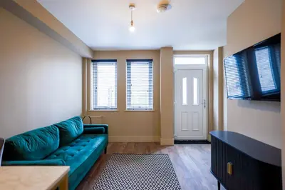 a living room with a green couch and windows at Netherbrae Apartment in Oban