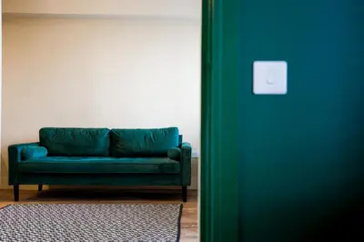 a green couch in a room with a wall at Netherbrae Apartment in Oban