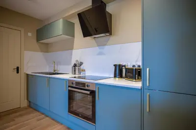 a kitchen with blue cabinets and a stove and refrigerator at Netherbrae Apartment in Oban