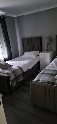 a bedroom with two beds and a dresser and a bedskirts at The Cottage in Kirk of Shotts