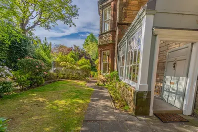 a brick house with a door and a yard at Victorian Charm - Lush Garden, Shops and Parking in Edinburgh