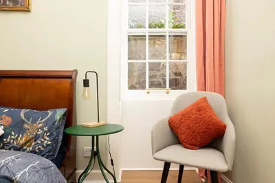 a bedroom with a chair and a table and a window at Stylish 1-Bedroom Edinburgh Apartment in Edinburgh