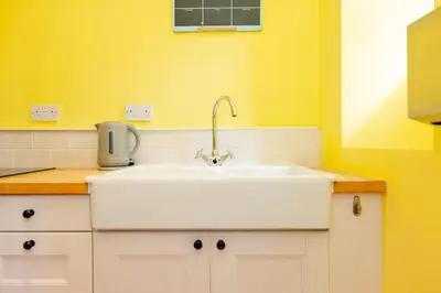 a white sink in a kitchen with yellow walls at Stylish 1-Bedroom Edinburgh Apartment in Edinburgh