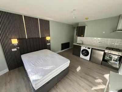 a small bedroom with a bed and a kitchen at The Dixon - Commonwealth Games 2026 in Glasgow