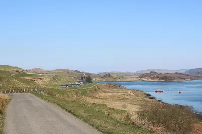 a road on a hill next to a body of water at Sula in Oban
