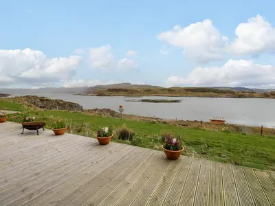 a deck with potted plants and a view of a lake at Fladda in Oban