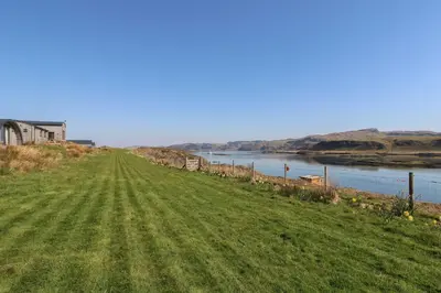 a grassy field next to a body of water at Fladda in Oban