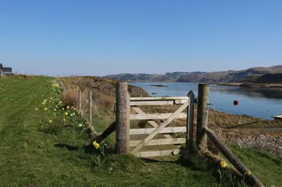 a wooden gate in the grass next to a river at Scarba in Oban