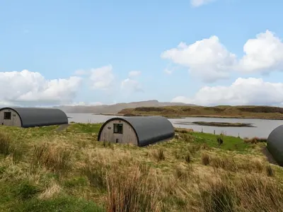 three domes in a field next to a body of water at Erraid in Oban