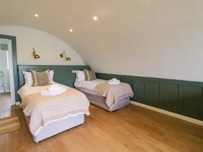 two beds in a room with green walls and wooden floors at Insh in Oban
