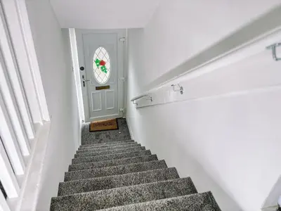 a staircase leading to a white door with areath on the window at Itohan 3-bed Cottage Flat in Glasgow