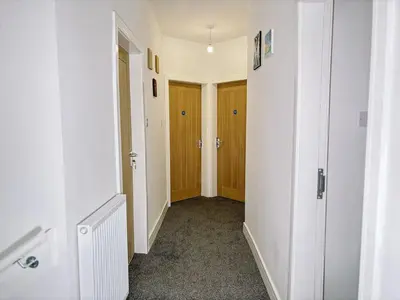 an empty hallway with white walls and wooden doors at Itohan 3-bed Cottage Flat in Glasgow