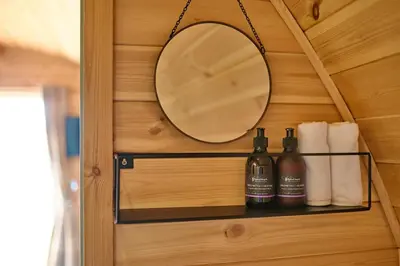 a bathroom with a mirror and a shelf with toiletries at The Pods at 7 Black Crofts in Oban