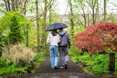 a man and woman walking down a path with an umbrella at Hamilton Residence - Private Main Door 1BR in Glasgow