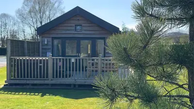 a small cabin with a porch and a fence at The Tummel Lodge with Hot Tub in Crieff in Crieff