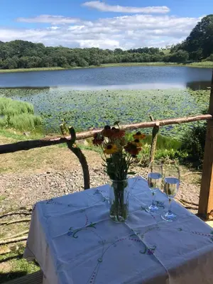 a table with a vase of flowers and two glasses at Barmoffity Shepherds Hut in Kirkpatrick Durham