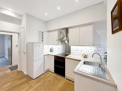 a white kitchen with a sink and a refrigerator at 2 bedroom, newly-renovated, comfortable town centre apartment! in Oban
