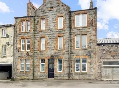 an old brick building with white windows on a street at 2 bedroom, newly-renovated, comfortable town centre apartment! in Oban