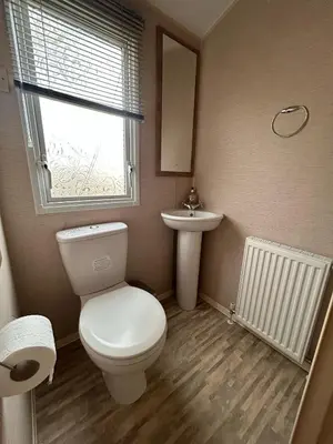 a bathroom with a toilet and a sink and a window at New Hampton 36 in Dunoon