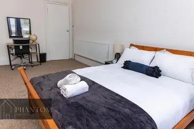 a bedroom with a large bed with towels on it at Complexx Suite in Glasgow
