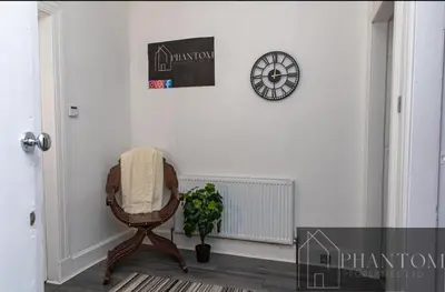 a room with a chair and a clock on the wall at Complexx Suite in Glasgow
