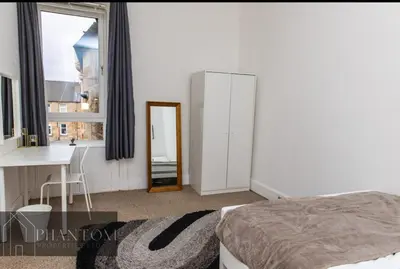 a bedroom with a bed and a desk and a mirror at Complexx Suite in Glasgow