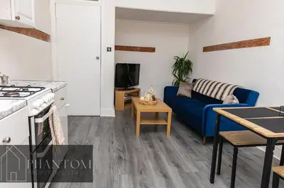 a kitchen and a living room with a blue couch at Complexx Suite in Glasgow