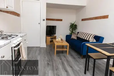 a kitchen and a living room with a blue couch at Complexx Suite in Glasgow