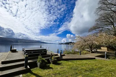 a bench on a dock next to a lake at Fyne Edge - A Luxurious Lochside Haven in Minard