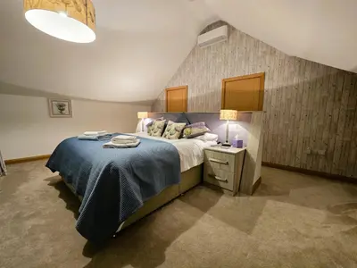 a bedroom with a large bed with a blue blanket at Fyne Edge - A Luxurious Lochside Haven in Minard