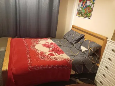 a bedroom with a bed with a red comforter at Kaffuhsmartt in Drumchapel